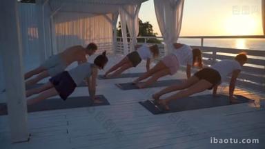 年轻人们练习瑜伽海路在黎明慢动作的露台上